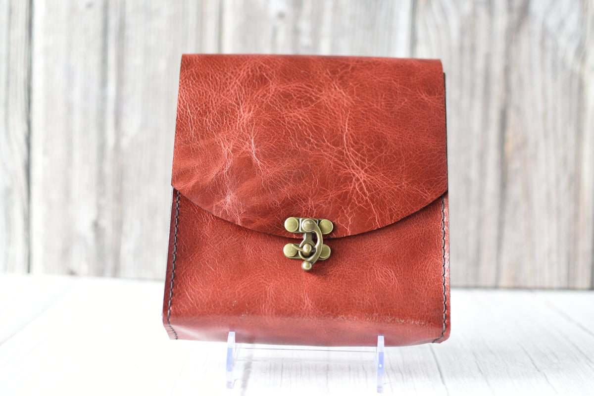 Red leather purse with a antique brass clasp on a white background