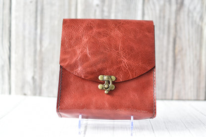 Red leather purse with a antique brass clasp on a white background