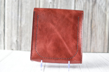Red leather purse with a antique brass clasp on a white background