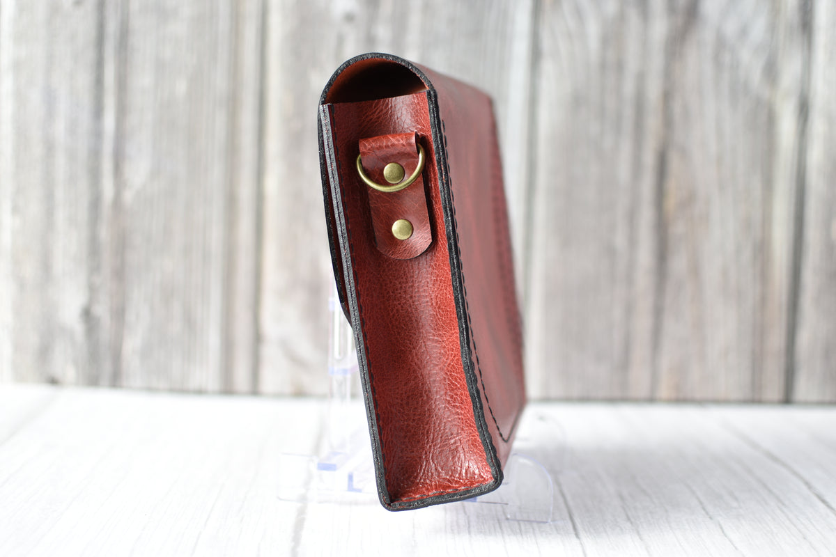 Red leather purse with a antique brass clasp on a white background