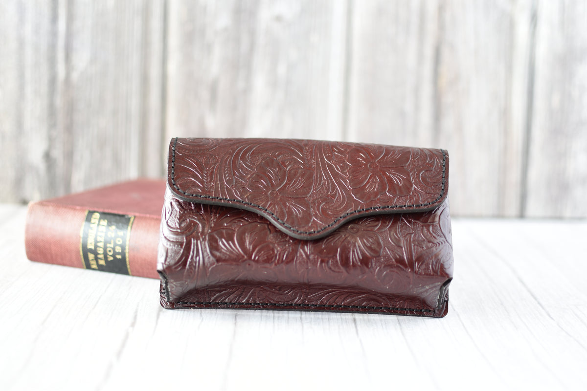 Deep Red leather cell phone purse with embossed design on a white surface